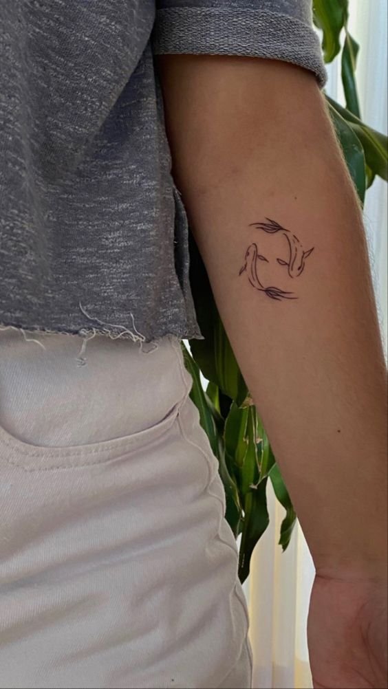 Hình xăm cá nhỏ phong cách blackwork trên cánh tay, chi tiết tối giản, ảnh HD.