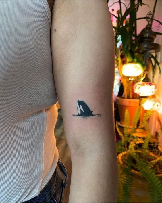 Hình xăm cá voi mini trên cánh tay, phong cách blackwork đơn giản, ảnh chất lượng HD.