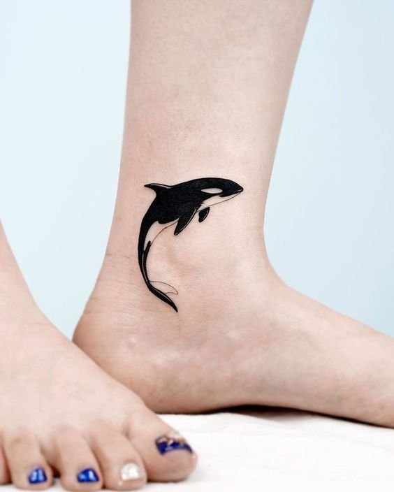Hình xăm cá voi sát thủ mini trên mắt cá chân, phong cách blackwork, chi tiết rõ nét, ảnh HD.