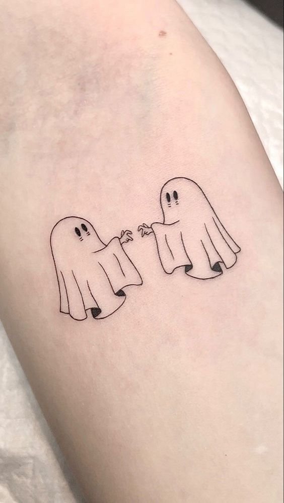 Hình xăm hai con ma mini trên cánh tay, phong cách blackwork, chi tiết rõ nét, độ phân giải HD.