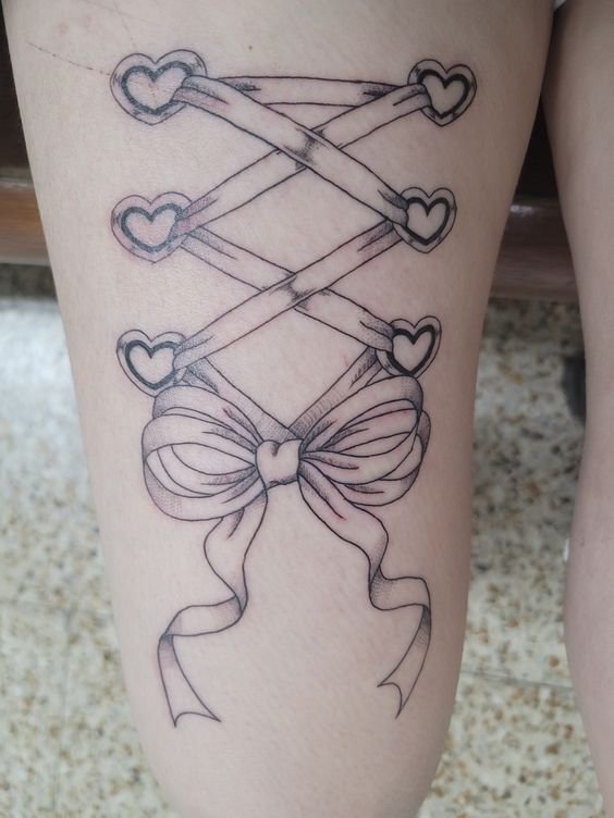 Hình xăm nơ và dây ruy băng phong cách blackwork trên đùi, chi tiết rõ nét, độ phân giải HD.
