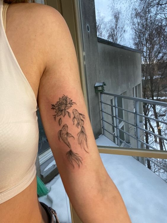 Hình xăm cá koi và hoa sen trên bắp tay, phong cách blackwork, chi tiết rõ nét, ảnh HD.