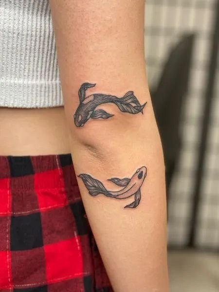 Hình xăm cá chép mini trên cánh tay, phong cách blackwork, chi tiết rõ nét. Ảnh HD.