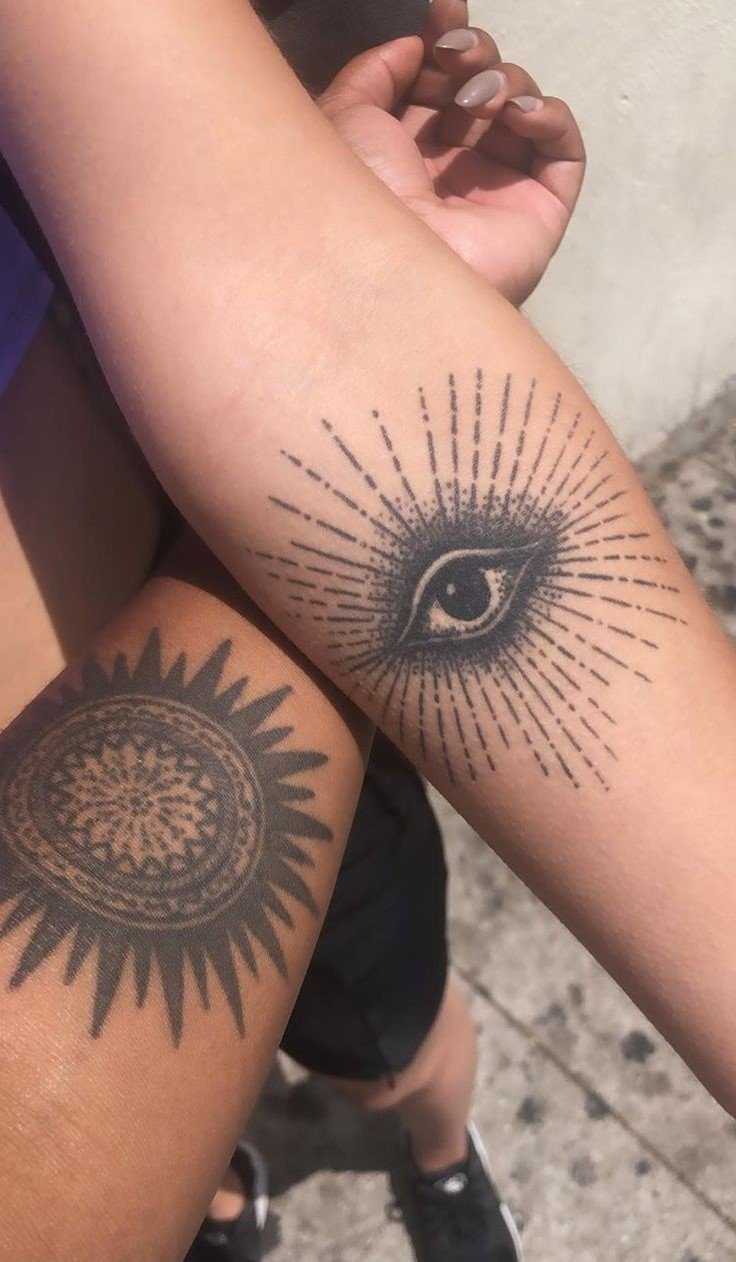 Hình xăm mắt và mặt trời trên cánh tay, phong cách blackwork, chi tiết rõ nét, ảnh HD.