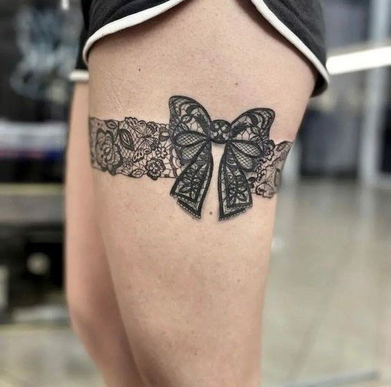 Hình xăm nơ ren đen trên đùi, phong cách blackwork tinh xảo, độ chi tiết cao, ảnh độ phân giải HD.