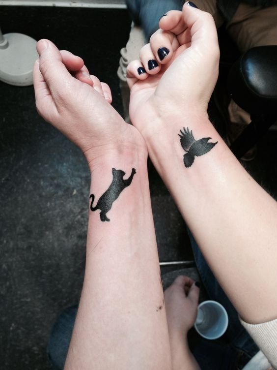 Hình xăm tối giản hình mèo và chim ở cổ tay, phong cách blackwork, độ phân giải HD.