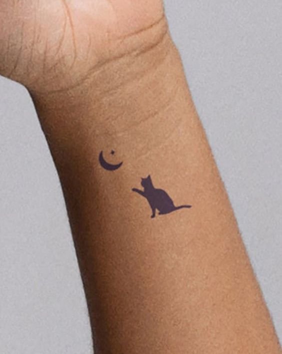 Hình xăm mini mèo và trăng trên cổ tay, phong cách blackwork, ảnh HD rõ nét.