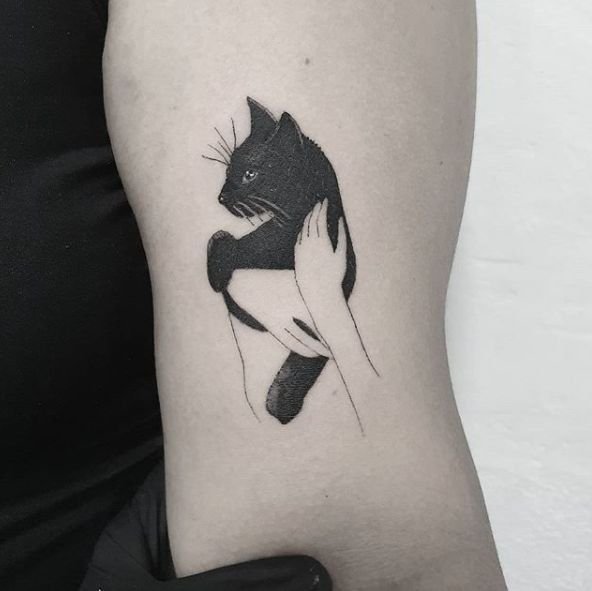 Hình xăm mèo ôm trên bắp tay, phong cách blackwork, chi tiết rõ nét, ảnh HD.