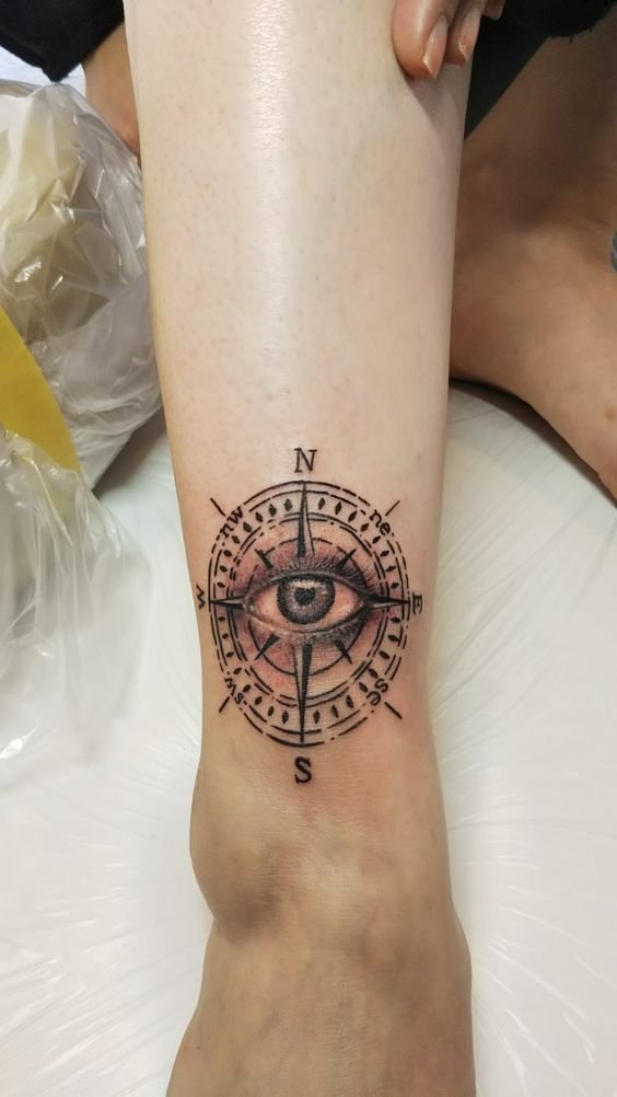 Hình xăm la bàn có mắt phong cách blackwork ở chân, chi tiết sắc nét, độ phân giải HD.