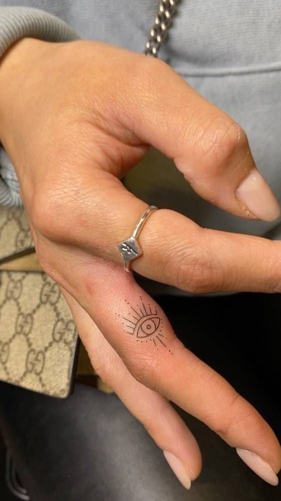 Hình xăm con mắt mini trên ngón tay, phong cách blackwork tối giản, ảnh HD chi tiết.
