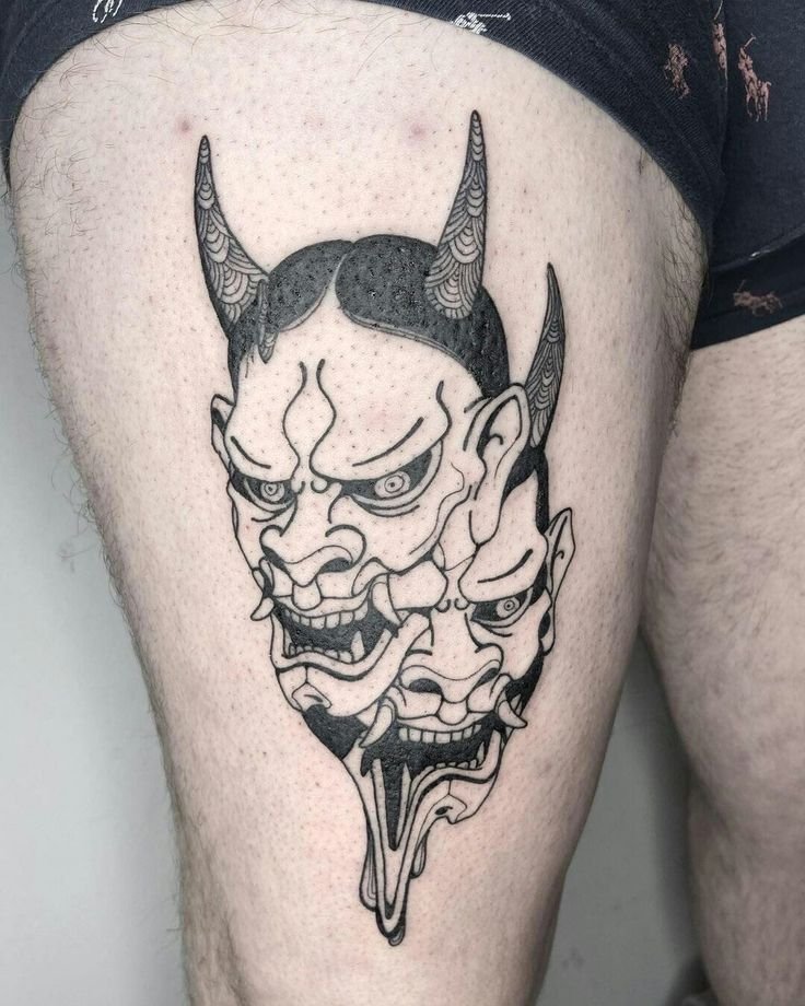 Hình xăm mặt nạ Oni phong cách blackwork trên đùi, chi tiết rõ nét, ảnh độ phân giải cao.