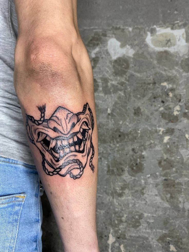 Hình xăm mặt nạ quỷ trên cánh tay, phong cách blackwork chi tiết, ảnh chất lượng HD.