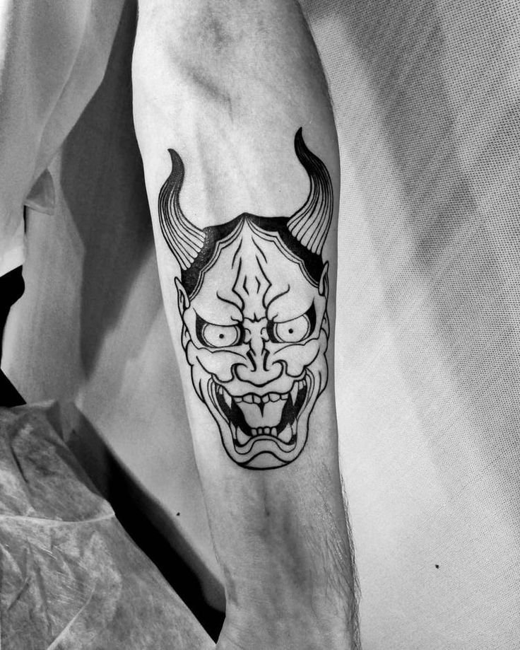 Hình xăm mặt nạ quỷ trên cánh tay, phong cách blackwork, chi tiết sắc nét, độ phân giải HD.