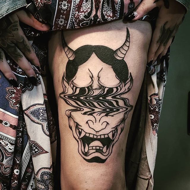 Hình xăm mặt quỷ phong cách blackwork trên đùi, chi tiết rõ nét, ảnh HD.