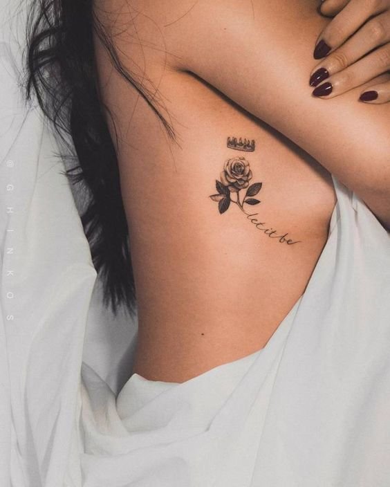 Hình xăm hoa hồng đen nhỏ gọn và đầy quyến rũ Hình xăm hoa hồng và chữ phong cách blackwork trên sườn, chi tiết sắc nét, độ phân giải HD.