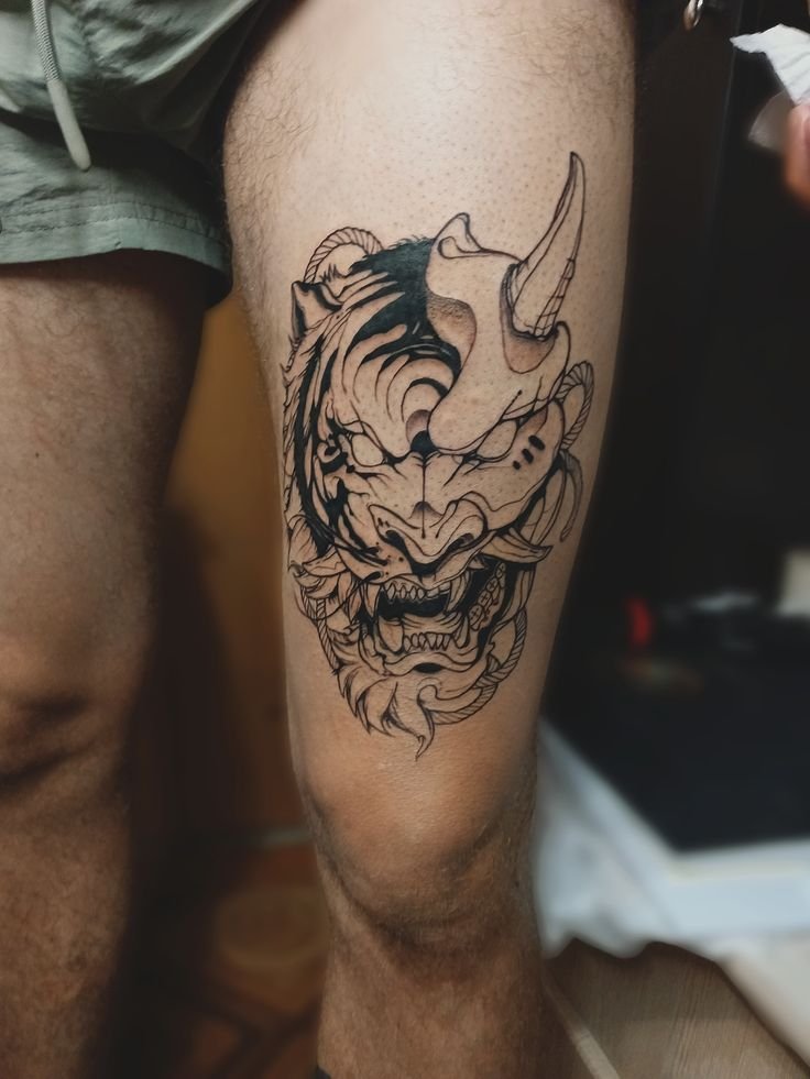 Hình xăm Oni đen trắng trên đùi, phong cách blackwork, chi tiết rõ nét, ảnh HD.
