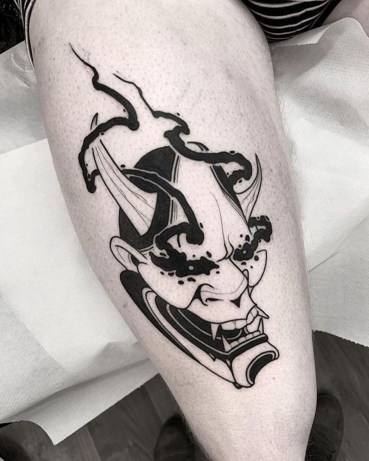 Hình xăm mặt nạ Oni phong cách blackwork trên đùi, chi tiết rõ nét, ảnh HD.