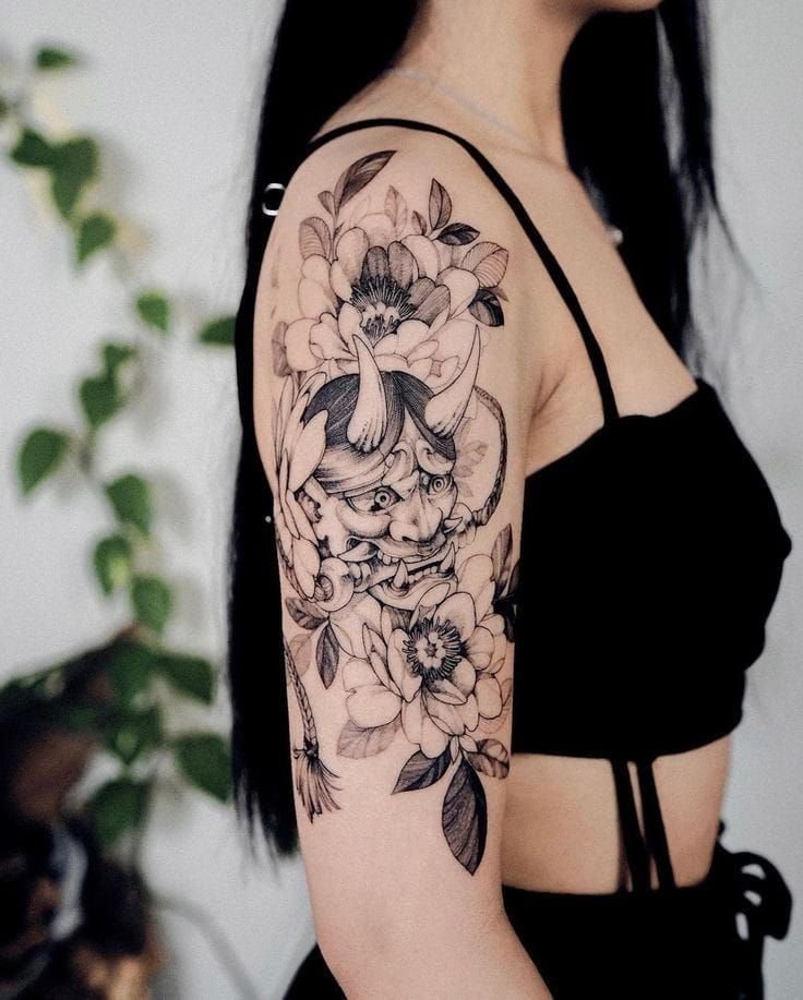 Hình xăm mặt quỷ và hoa trên tay, phong cách blackwork, chi tiết rõ nét, ảnh HD.