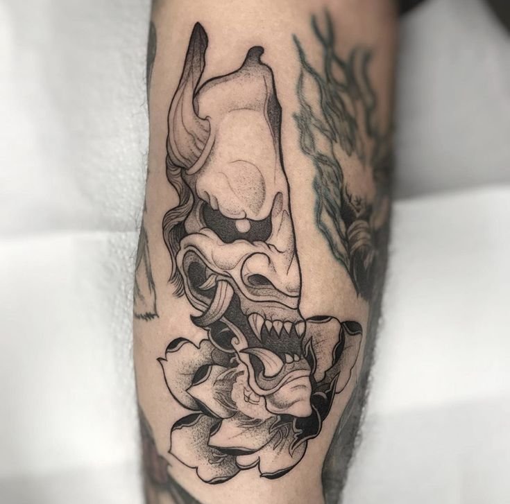 Hình xăm mặt nạ quỷ trên cánh tay, phong cách blackwork, chi tiết rõ nét, độ phân giải HD.