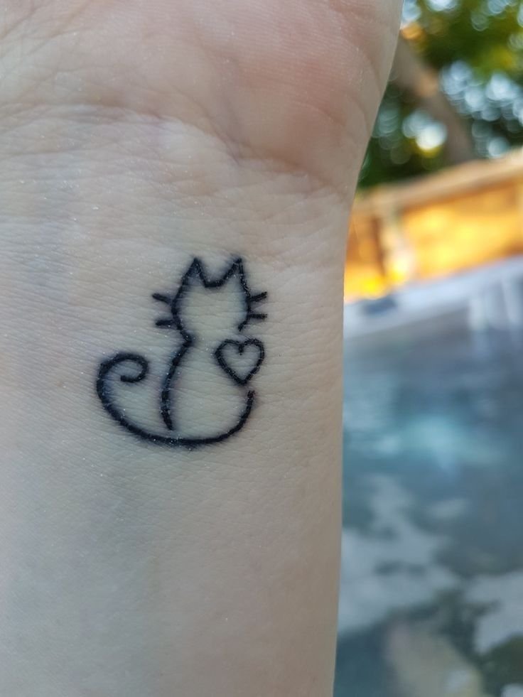 Hình xăm mini mèo đơn giản trên cổ tay, phong cách blackwork, ảnh độ phân giải cao.